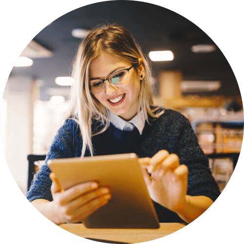 Smiling woman using tablet in library